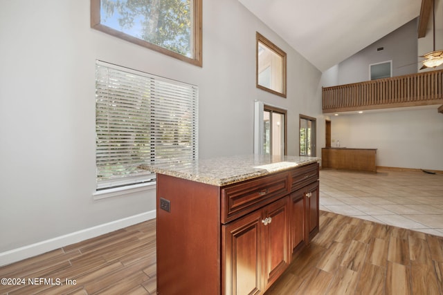 kitchen featuring plenty of natural light, light stone countertops, light hardwood / wood-style floors, and a kitchen island