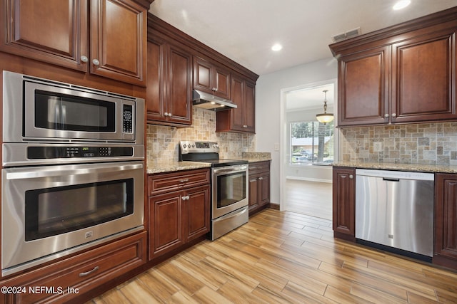 kitchen with backsplash, light wood-type flooring, light stone countertops, and appliances with stainless steel finishes