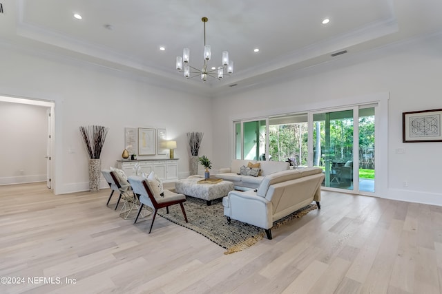 living room featuring a high ceiling, a raised ceiling, light wood-type flooring, and a chandelier