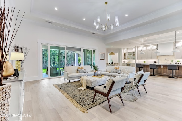 living room with an inviting chandelier, ornamental molding, light hardwood / wood-style floors, and a raised ceiling