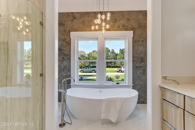 bathroom with a bathtub, tile flooring, a chandelier, and tile walls