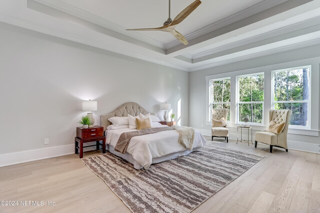 bedroom featuring ceiling fan, light hardwood / wood-style floors, a tray ceiling, and crown molding