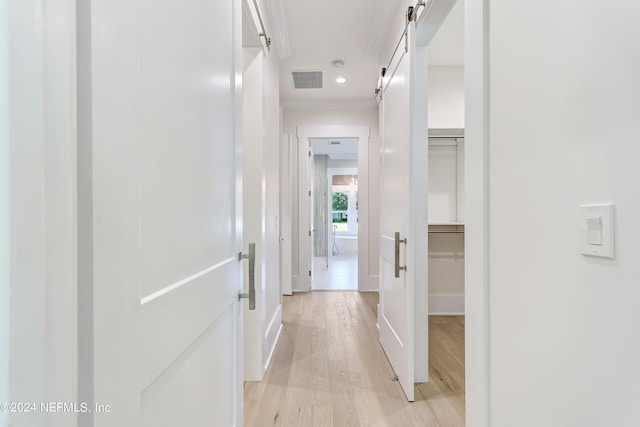 hallway with a barn door and light hardwood / wood-style floors