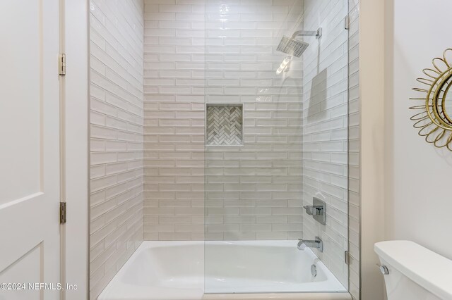 bathroom with toilet and tiled shower / bath combo