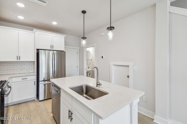 kitchen featuring tasteful backsplash, an island with sink, sink, white cabinets, and stainless steel appliances