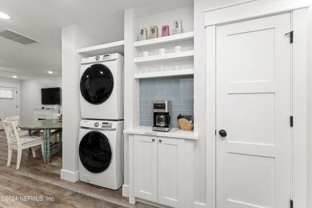 clothes washing area with stacked washer and dryer and hardwood / wood-style flooring