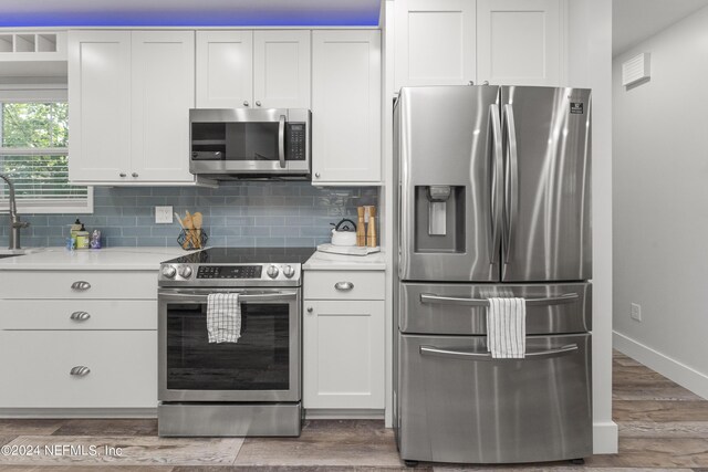 kitchen with backsplash, white cabinetry, and appliances with stainless steel finishes