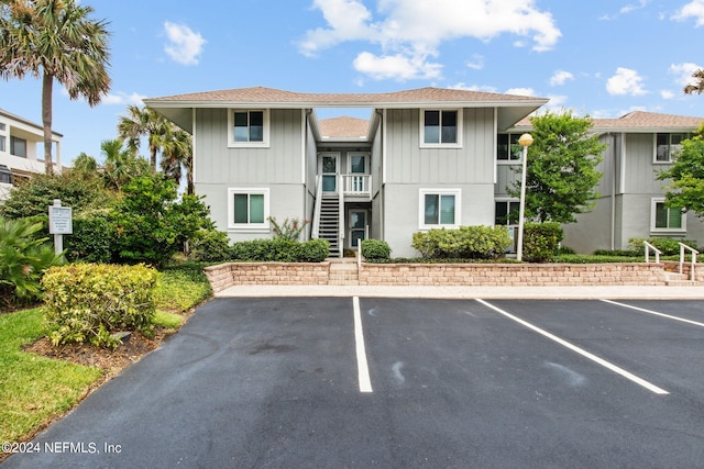 view of property with uncovered parking and stairway