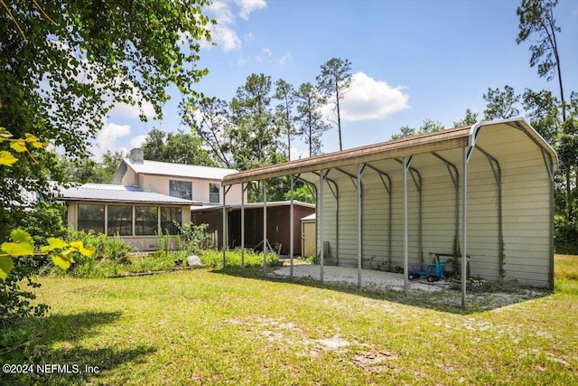 back of house featuring a sunroom, a lawn, and a carport