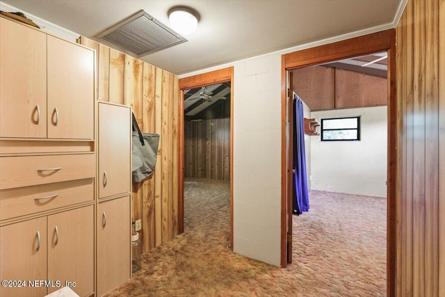 hallway featuring light colored carpet and wooden walls