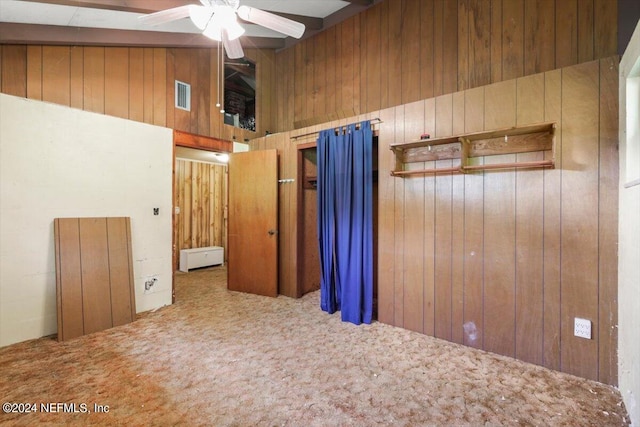 unfurnished room with a towering ceiling, carpet flooring, ceiling fan, and wood walls