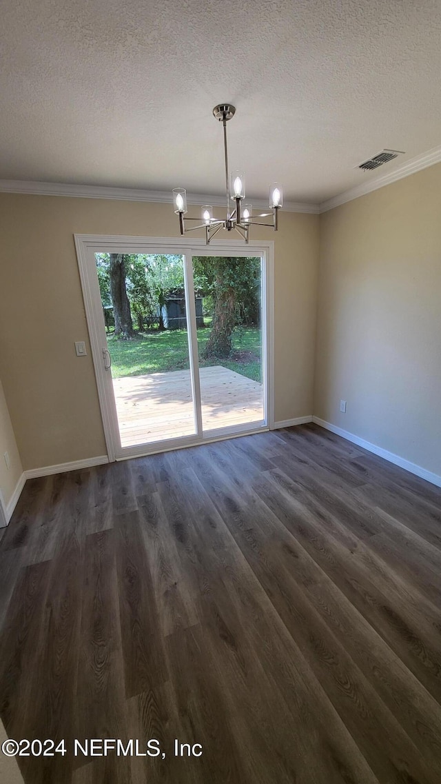 unfurnished dining area with a textured ceiling, a notable chandelier, dark hardwood / wood-style floors, and ornamental molding