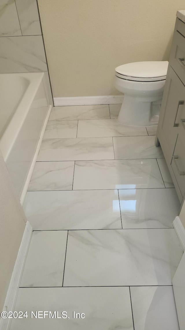 bathroom with vanity, toilet, and a tub