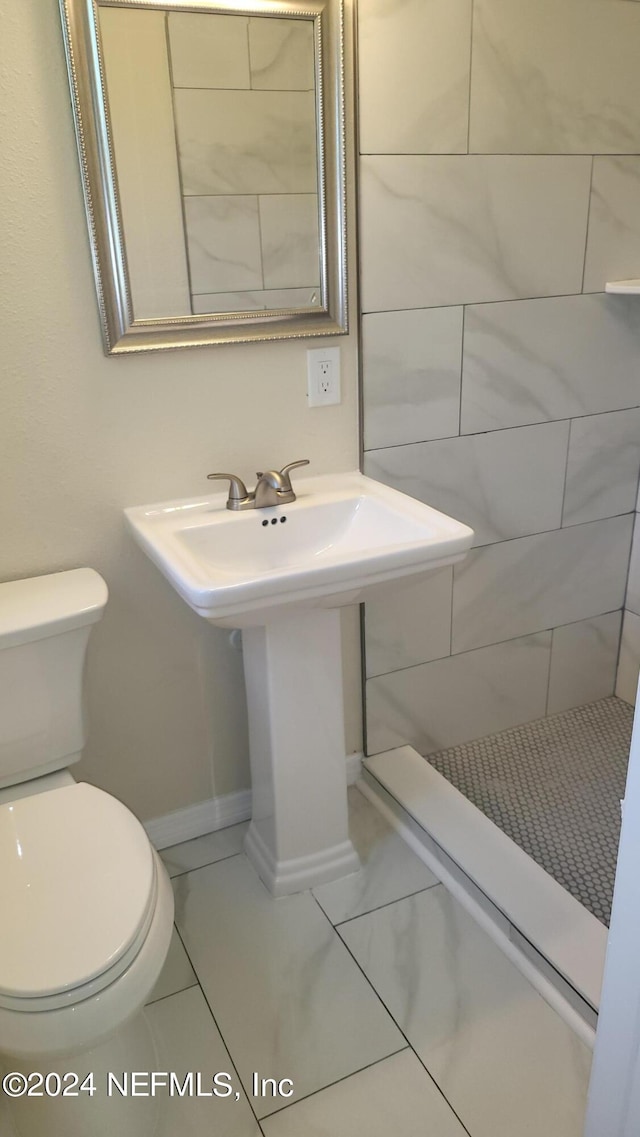 bathroom featuring a tile shower, tile patterned flooring, and toilet