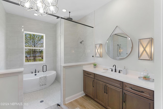 bathroom featuring hardwood / wood-style floors, vanity, an inviting chandelier, and independent shower and bath