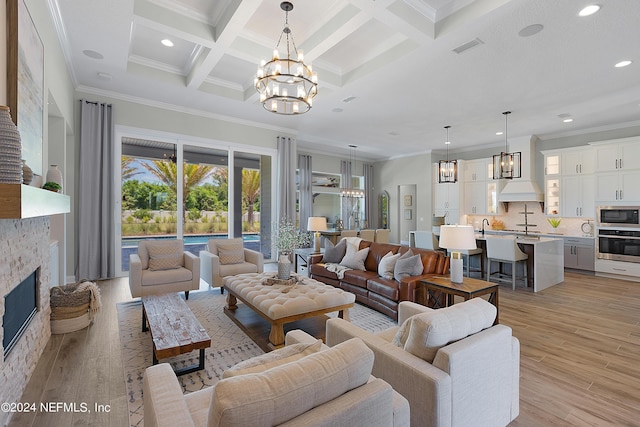 living room with a fireplace, ornamental molding, light wood-type flooring, and coffered ceiling