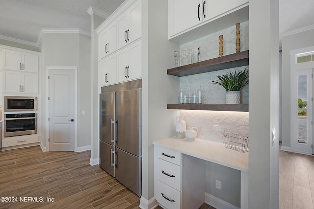 kitchen with built in appliances, white cabinets, ornamental molding, and light wood-type flooring