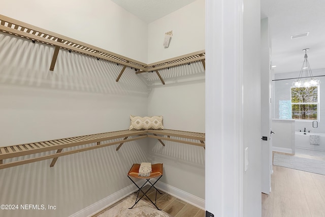 walk in closet with hardwood / wood-style floors and a notable chandelier