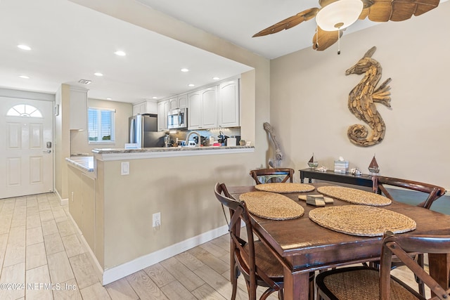 kitchen featuring backsplash, light wood-type flooring, white cabinetry, kitchen peninsula, and stainless steel appliances