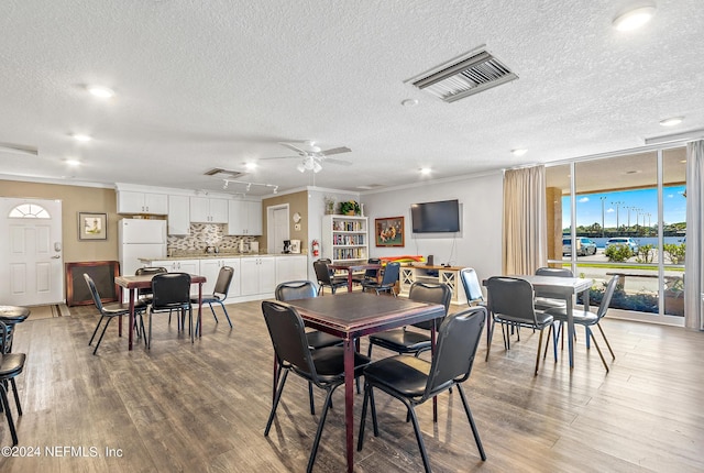 dining space featuring ceiling fan, rail lighting, light hardwood / wood-style floors, a textured ceiling, and ornamental molding