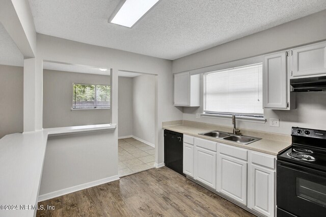 kitchen with a textured ceiling, black appliances, sink, light hardwood / wood-style flooring, and white cabinets