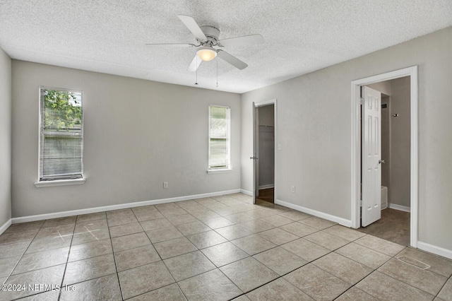 interior space featuring light tile patterned floors, a textured ceiling, and ceiling fan