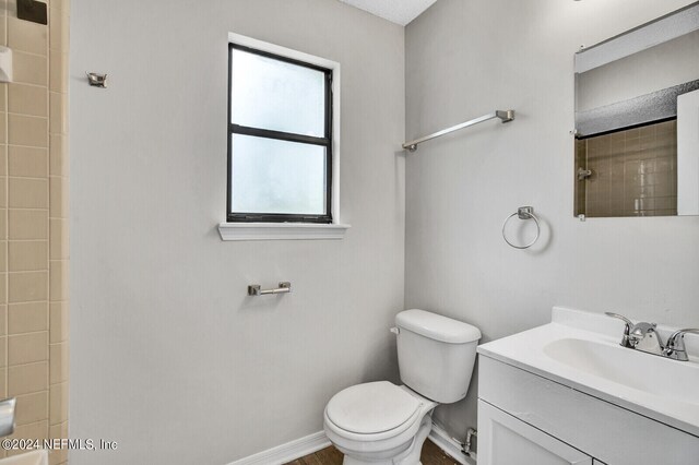 bathroom with tiled shower, vanity, and toilet