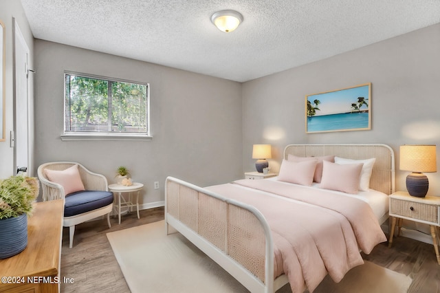 bedroom with light hardwood / wood-style floors and a textured ceiling