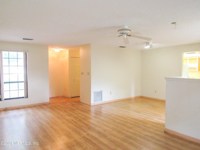 empty room with ceiling fan and light hardwood / wood-style flooring