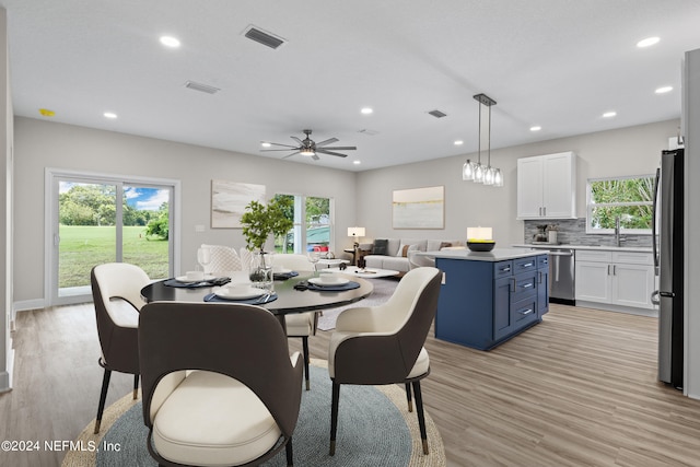 dining space with light wood-style floors, plenty of natural light, and visible vents