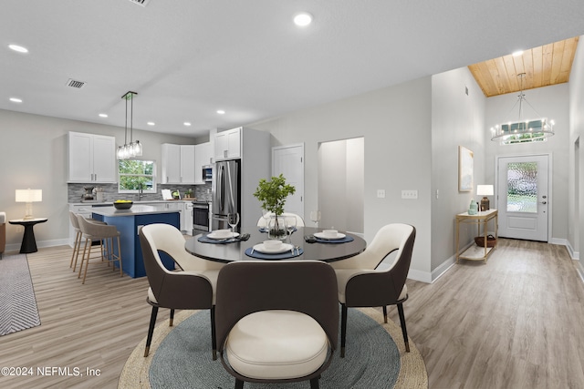 dining area with a wealth of natural light, a notable chandelier, light wood-style flooring, and baseboards