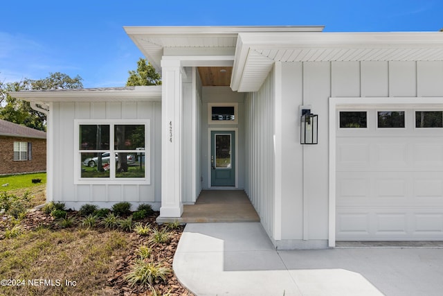 view of exterior entry featuring an attached garage and board and batten siding