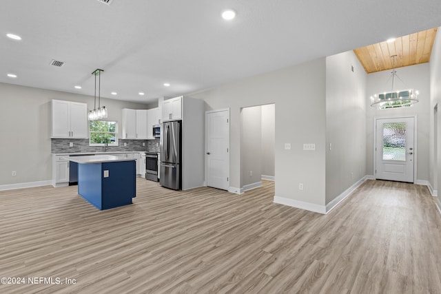 kitchen with white cabinetry, a kitchen island, a wealth of natural light, and an inviting chandelier