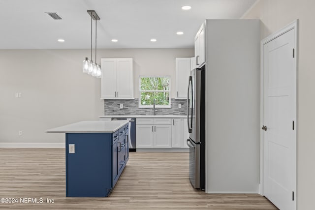 kitchen with light wood-type flooring, pendant lighting, white cabinetry, stainless steel appliances, and a center island