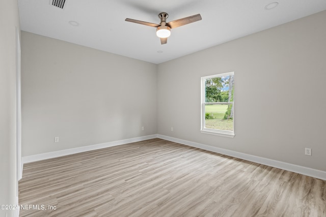 empty room featuring a ceiling fan, visible vents, light wood-style flooring, and baseboards