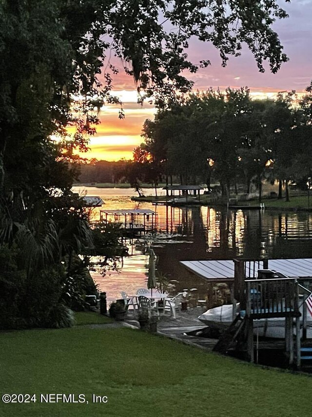 view of nearby features with a boat dock, a water view, and a yard