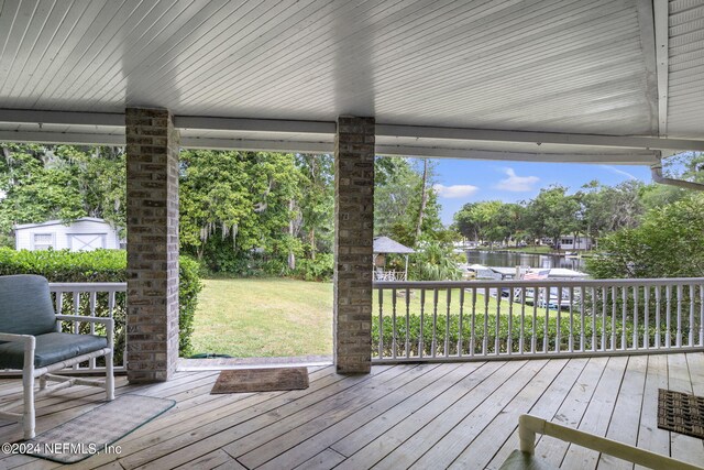 wooden deck with a water view and a yard