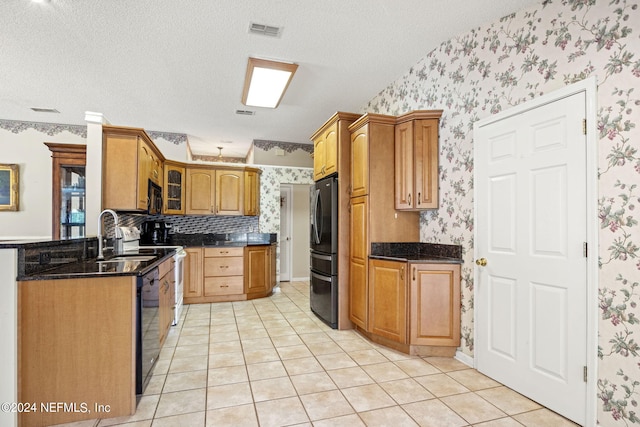 kitchen with visible vents, a sink, a textured ceiling, black appliances, and wallpapered walls