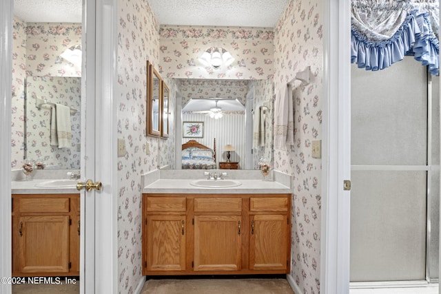 bathroom featuring walk in shower, vanity, ceiling fan, and a textured ceiling