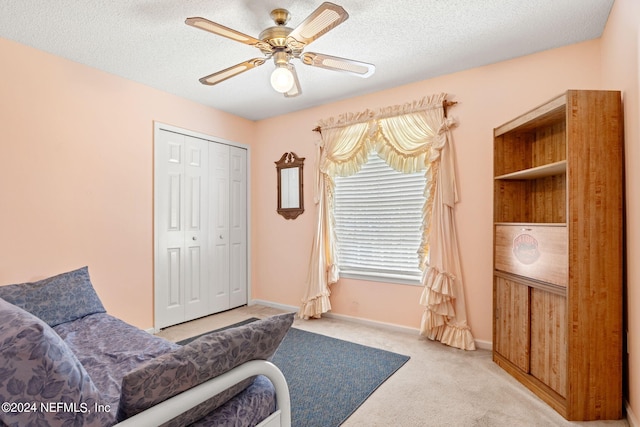 living area with a textured ceiling, carpet floors, a ceiling fan, and baseboards