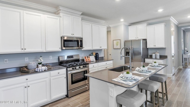 kitchen with stainless steel appliances, sink, a center island with sink, and white cabinets