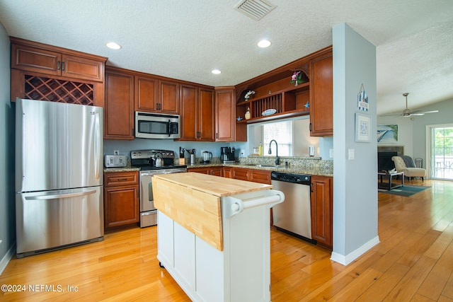 kitchen featuring wooden counters, light wood-type flooring, stainless steel appliances, ceiling fan, and sink