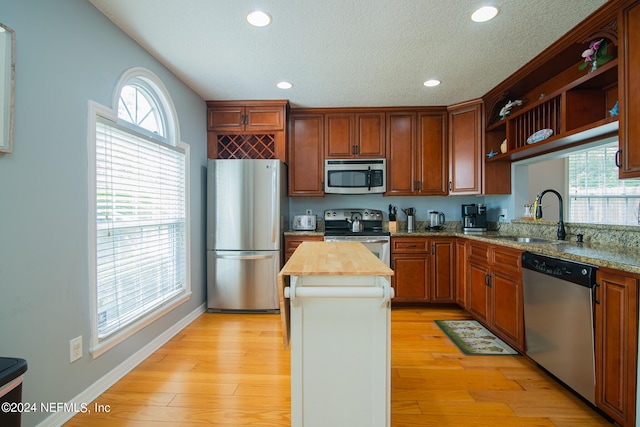 kitchen featuring appliances with stainless steel finishes, sink, light hardwood / wood-style floors, a kitchen island, and butcher block counters