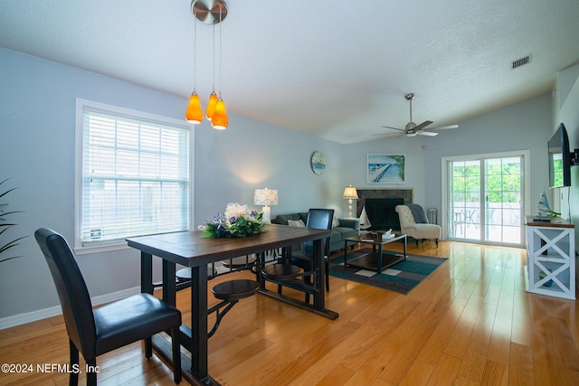 dining area with vaulted ceiling, a textured ceiling, light hardwood / wood-style floors, and ceiling fan with notable chandelier