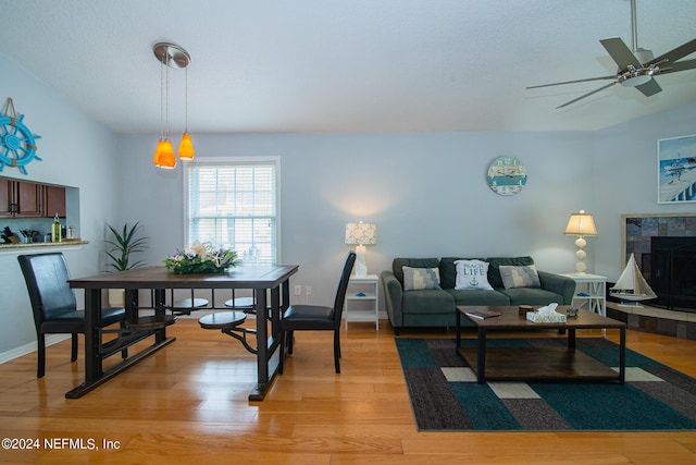 living room featuring a textured ceiling, vaulted ceiling, ceiling fan, light hardwood / wood-style flooring, and a fireplace