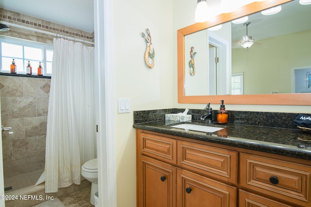 bathroom with a shower with curtain, vanity, toilet, and ceiling fan