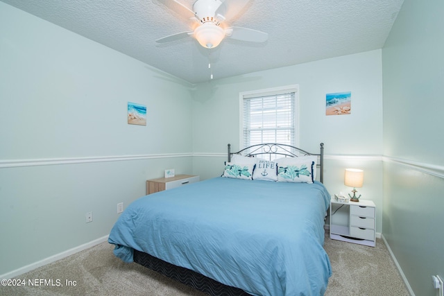 bedroom with a textured ceiling, light colored carpet, and ceiling fan