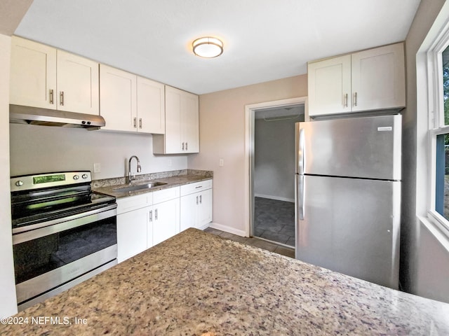 kitchen featuring light stone countertops, stainless steel appliances, tile patterned flooring, white cabinets, and sink