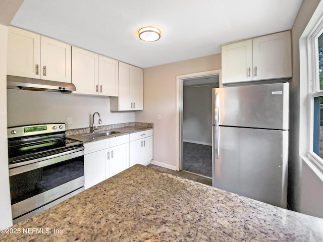 kitchen with light stone counters, baseboards, a sink, under cabinet range hood, and appliances with stainless steel finishes