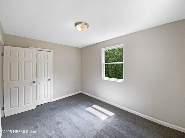 unfurnished bedroom with a closet, baseboards, and dark colored carpet